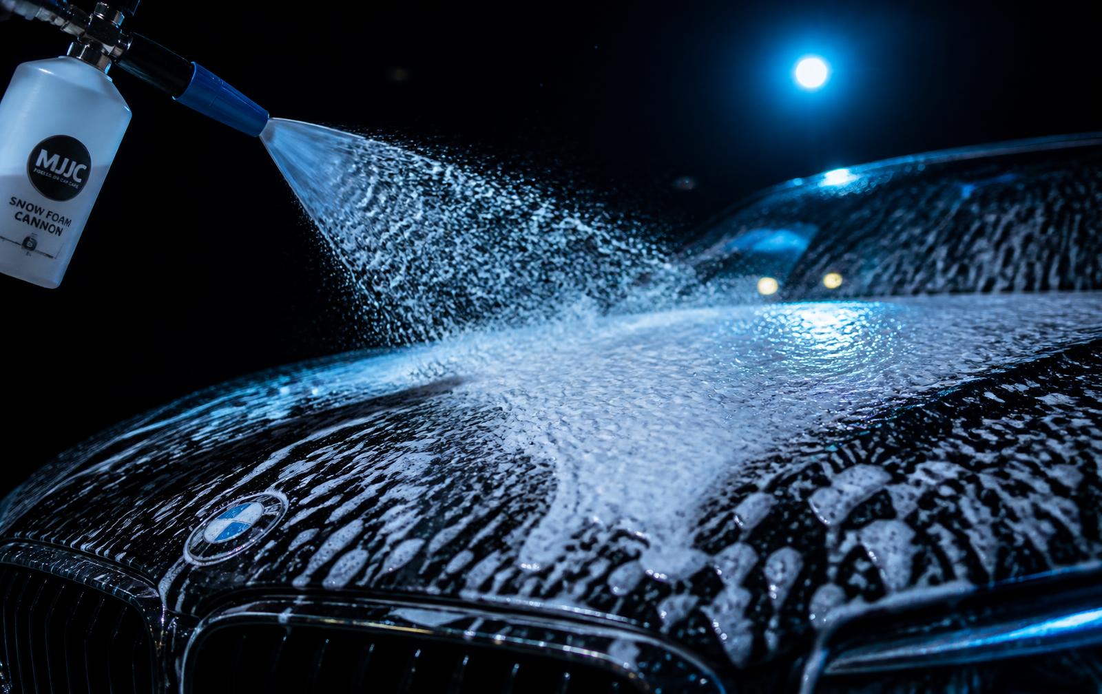 Snow foam applied across the hood of a glossy black car